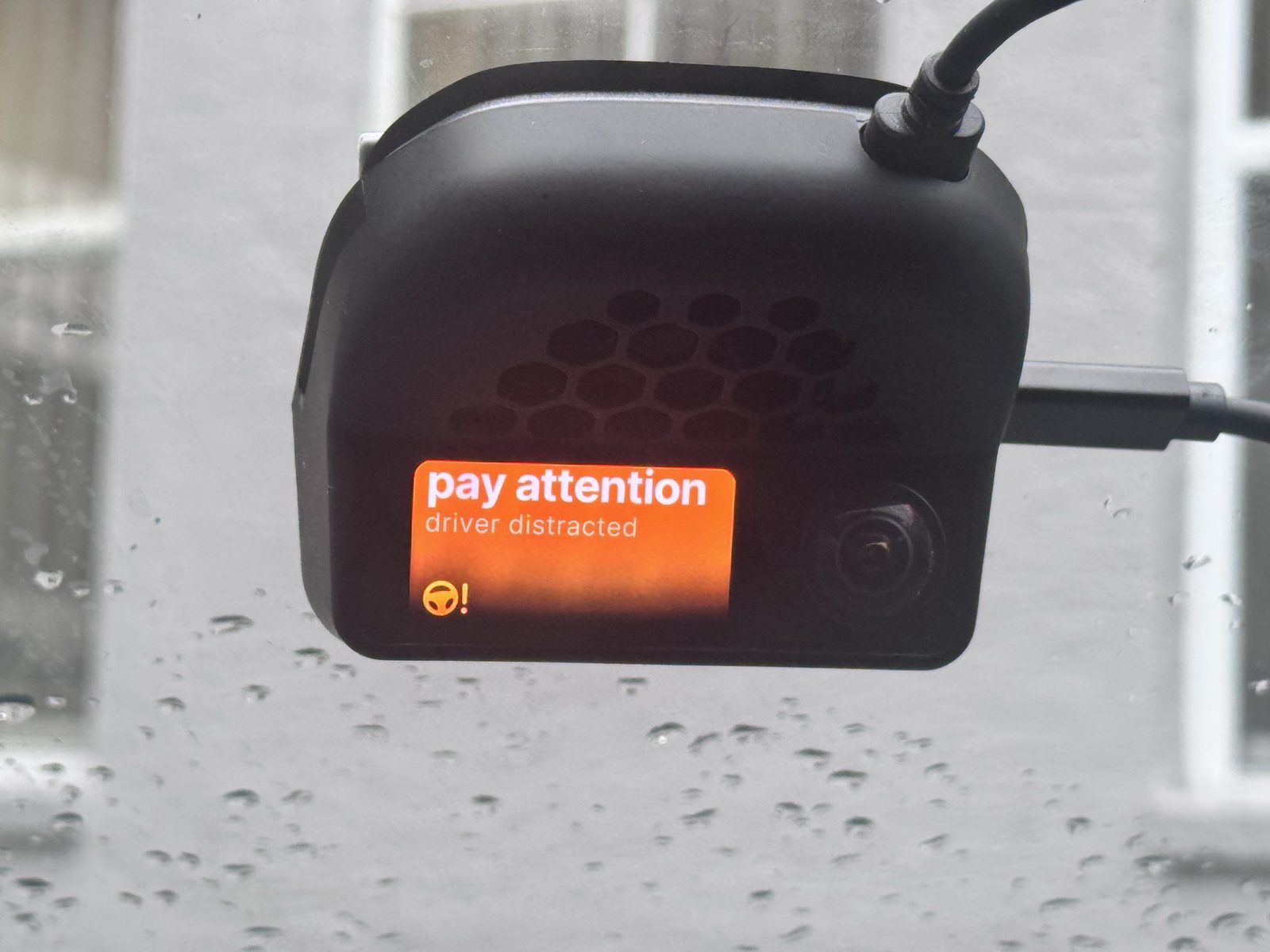 The device showing a 'pay attention — driver distracted' warning